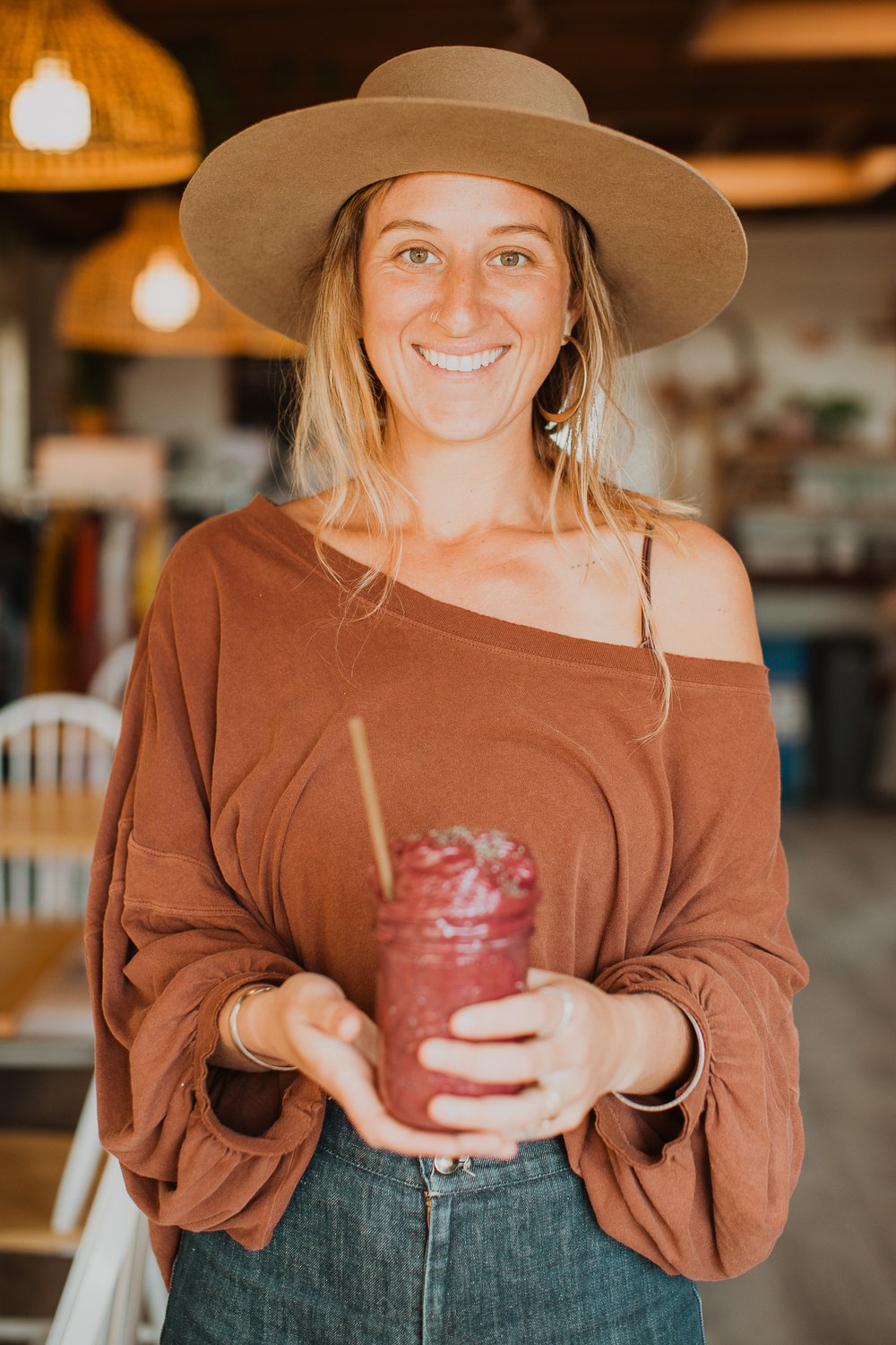 a woman with a hat holding a smoothie.