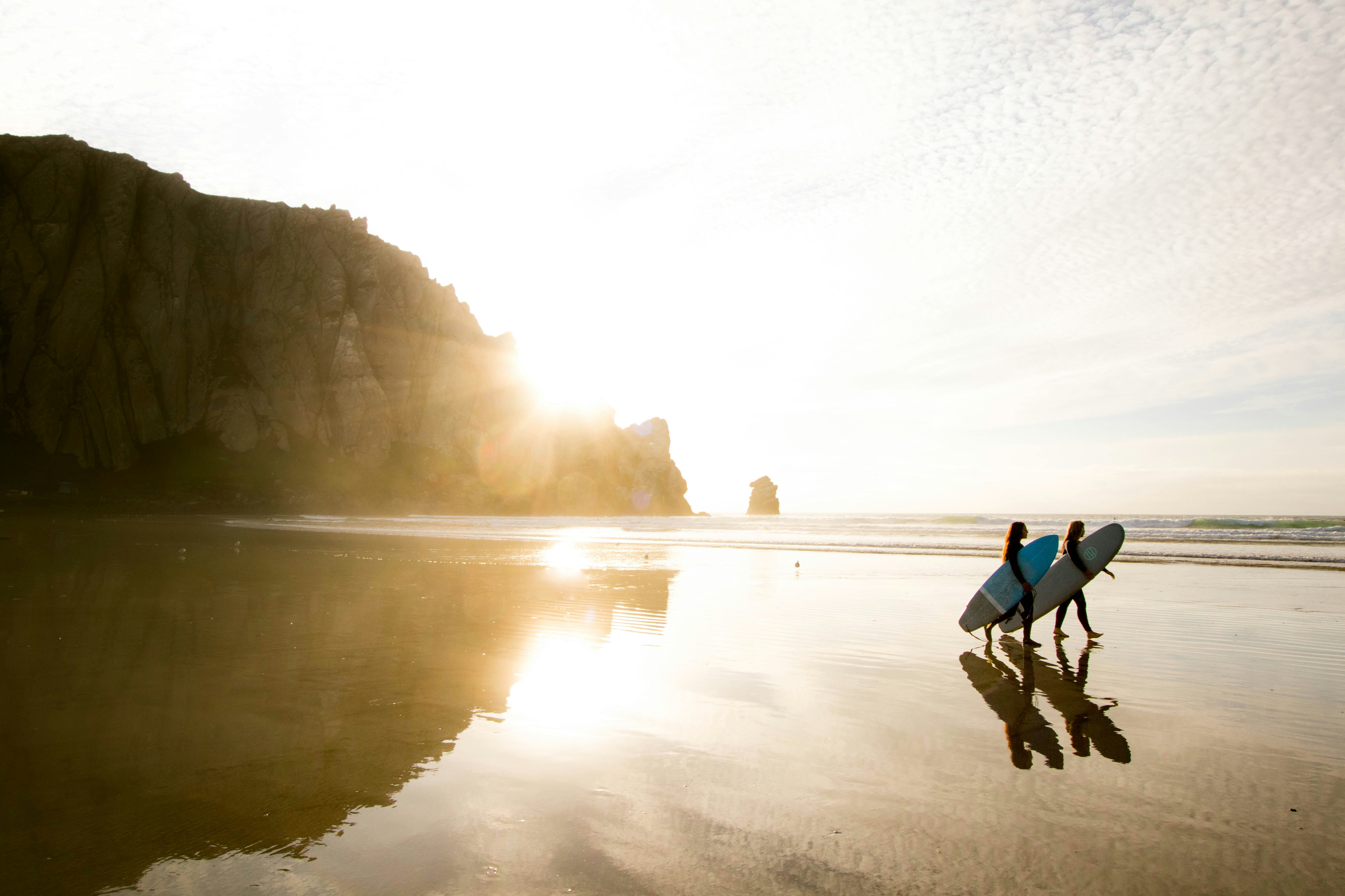 Morro Rock at sunset with surfers in the foreground.