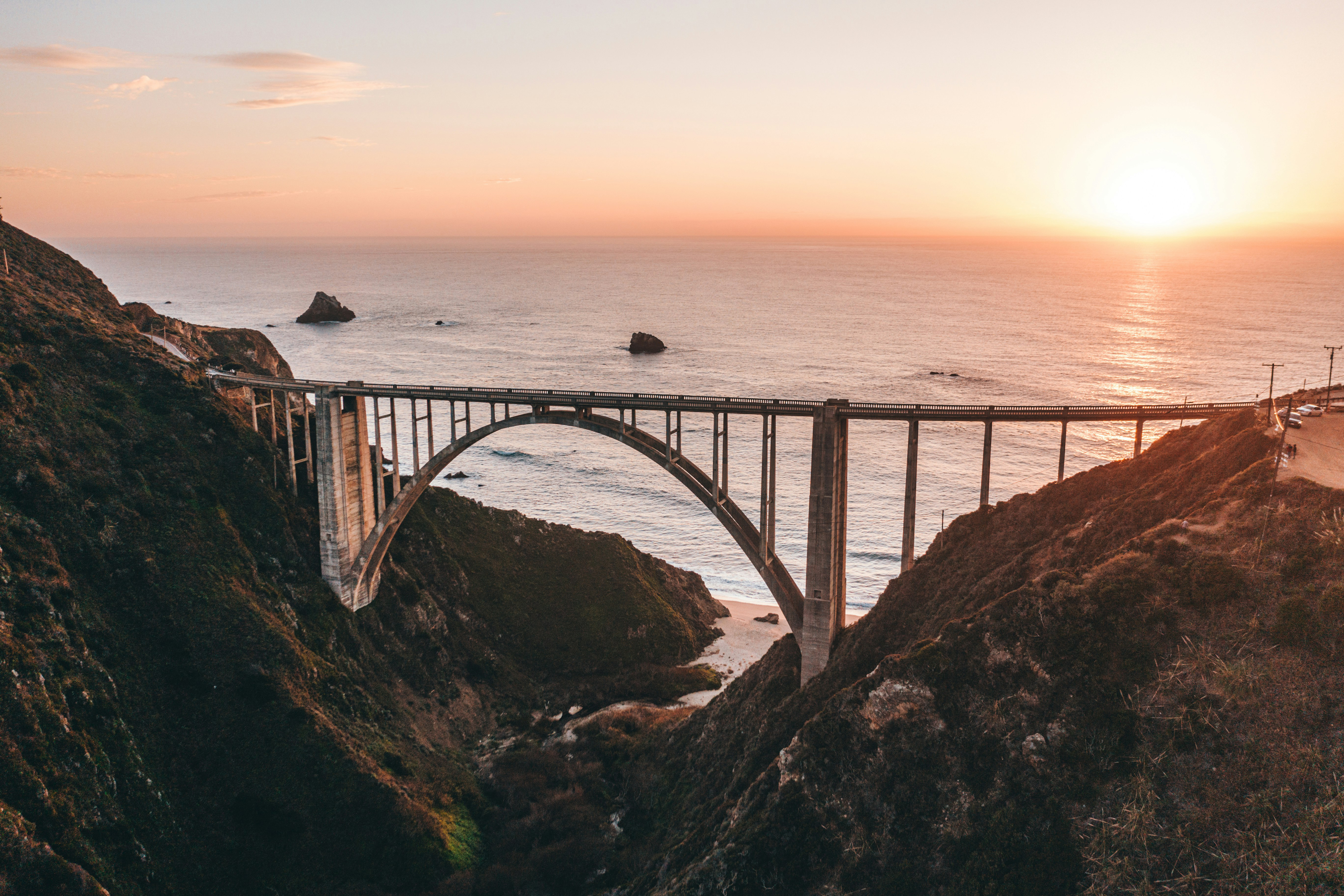 gray metal bridge over the sea during sunset.