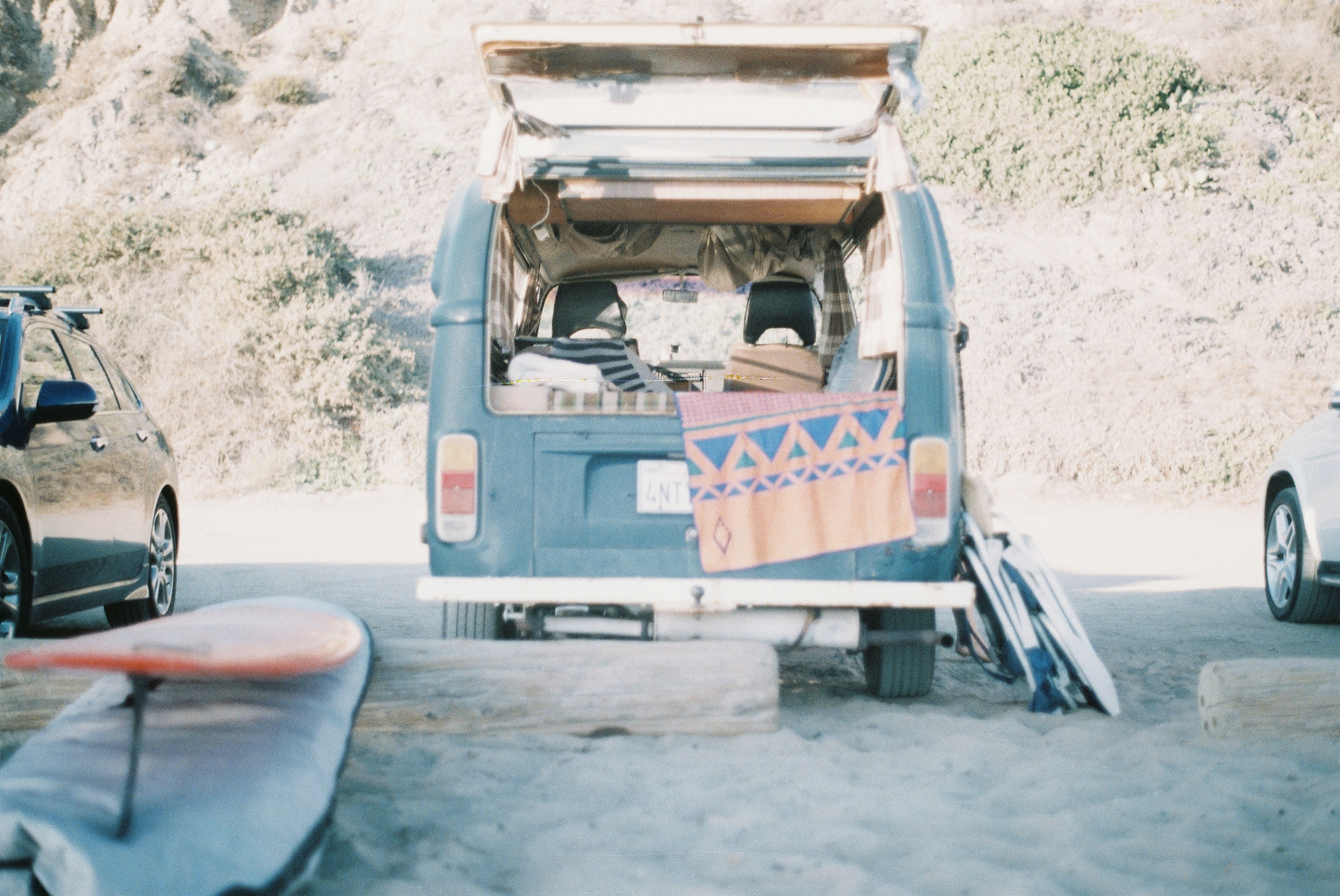 Van with towels and surfboards beside it.